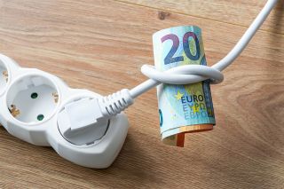 Foto: Weißes Elektrokabel wobei mit einem Knoten daran Geldscheine befestigt sind